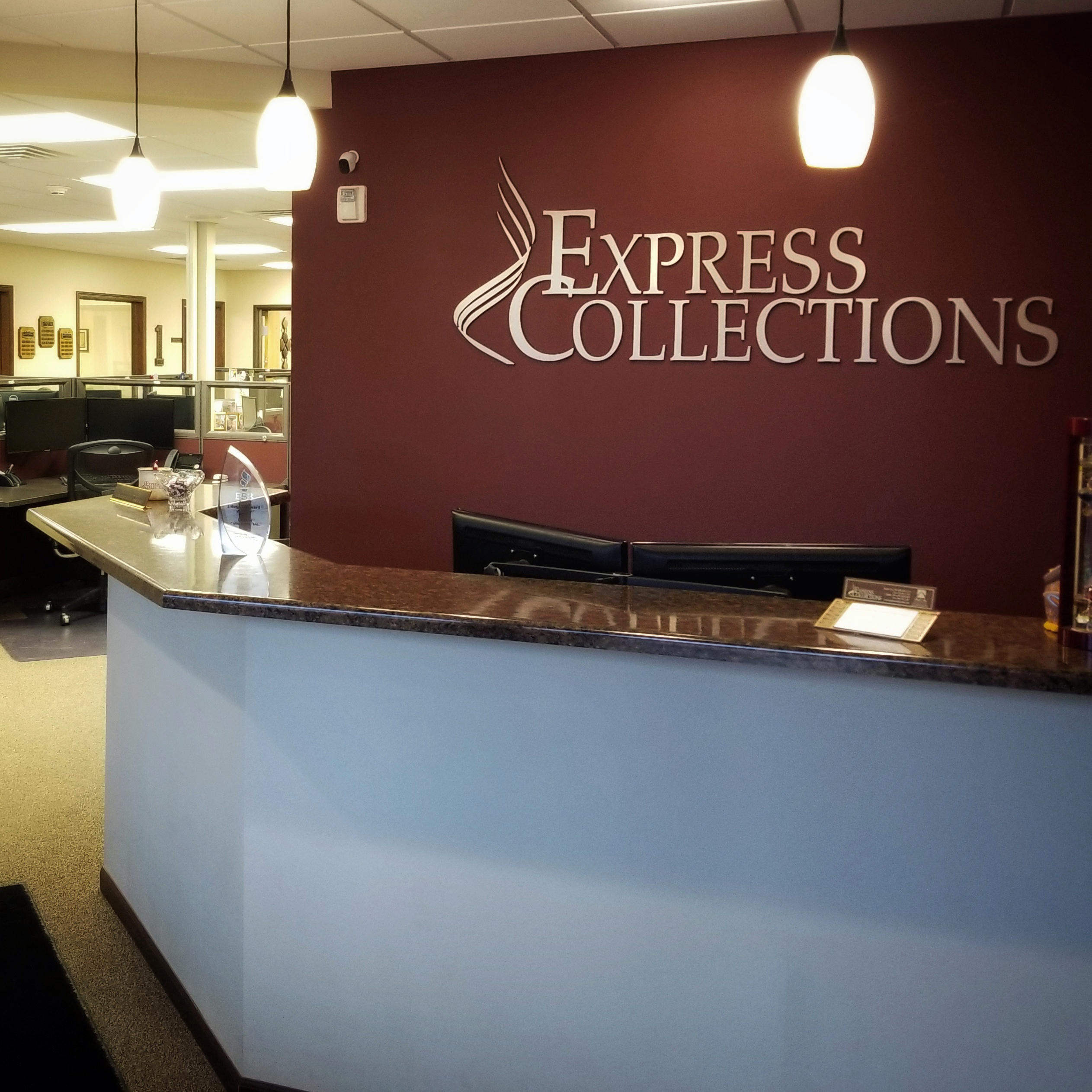 reception area with red backdrop and express collections logo behind the desk