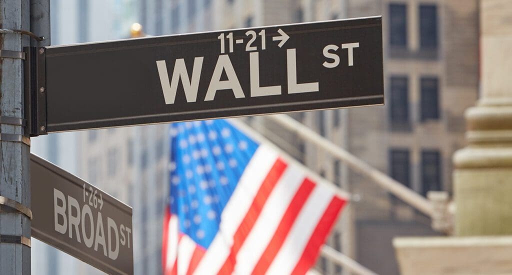 Wall Street sign near Stock Exchange with US flags