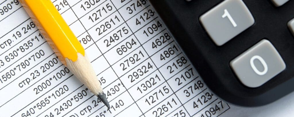 Close-up of a financial accounting document with columns of numbers, a yellow pencil, and a calculator keypad.